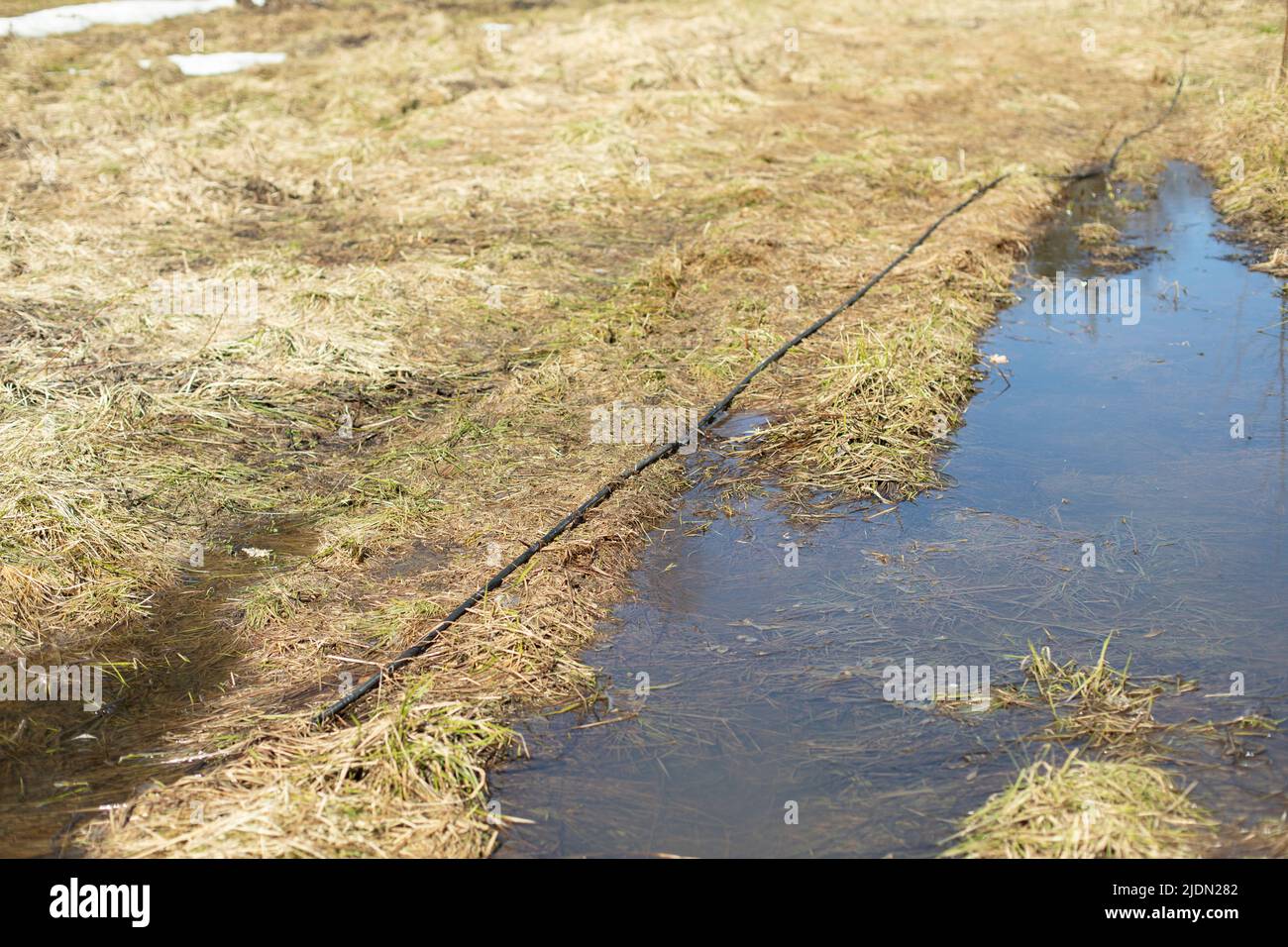 Wire in water. Electric wire on ground. Cable stretches across wet