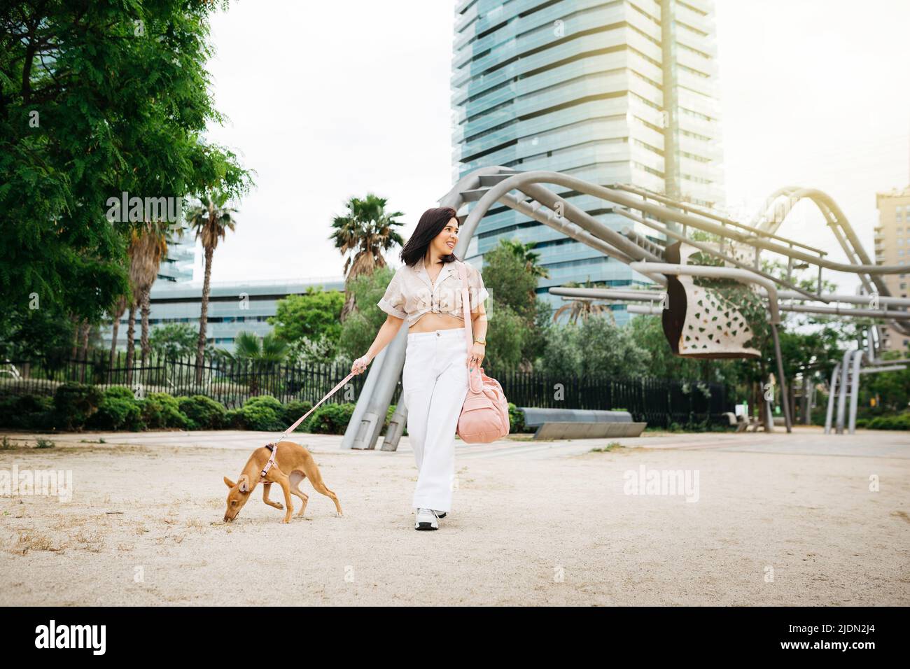 Young woman walking with her dog on a urban park Stock Photo