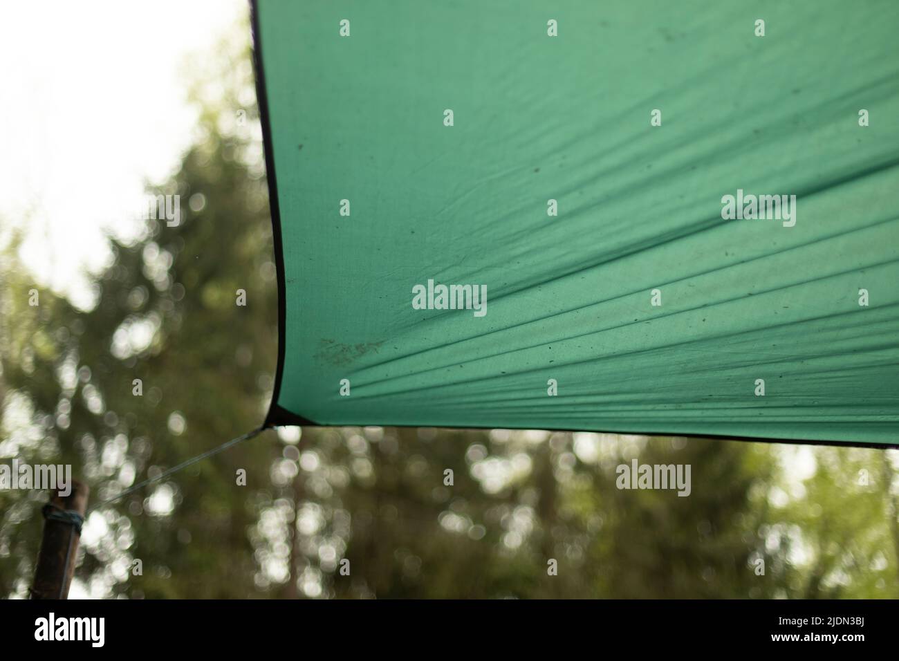 Awning is stretched on rope. Camping details. Green awning in nature