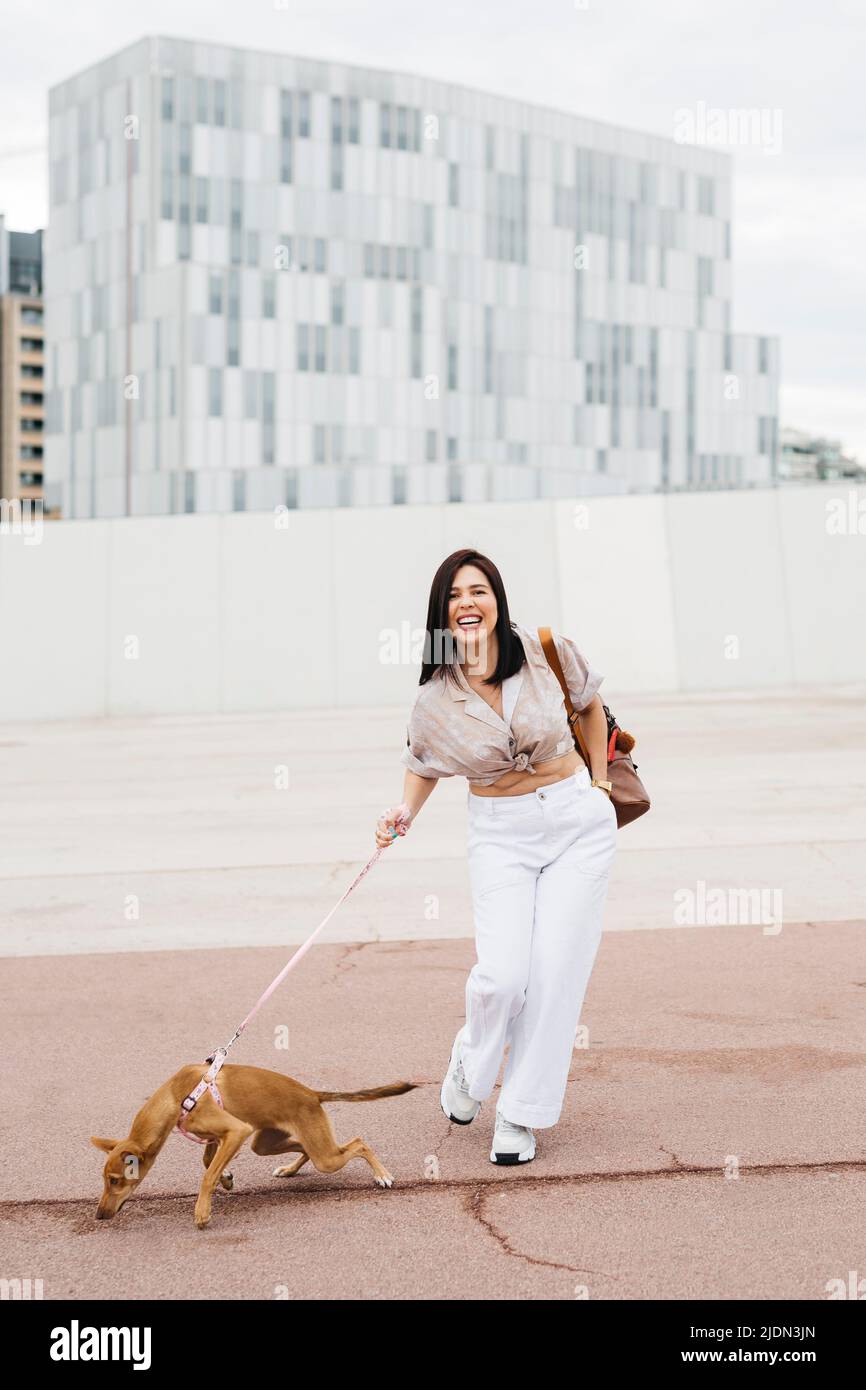 Young woman walking with her dog on the street Stock Photo