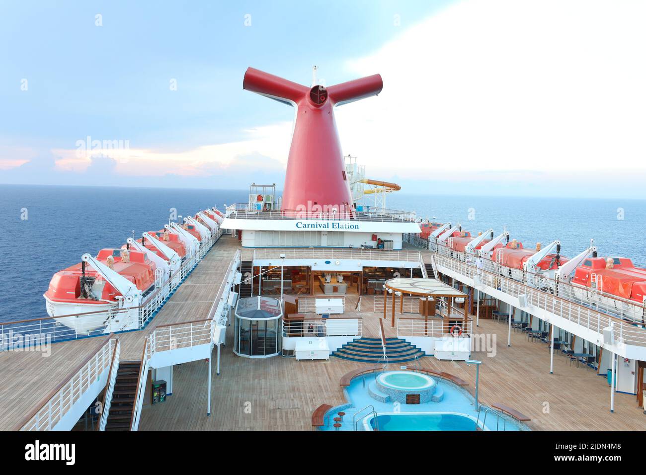 Panoramic shot of open decks and red funnel on CarnivalElation Carnival Valor, Carnival Fascination, blue sky with white clouds in the background. Stock Photo