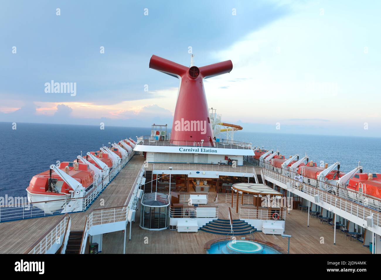 Panoramic shot of open decks and red funnel on CarnivalElation Carnival Valor, Carnival Fascination, blue sky with white clouds in the background. Stock Photo