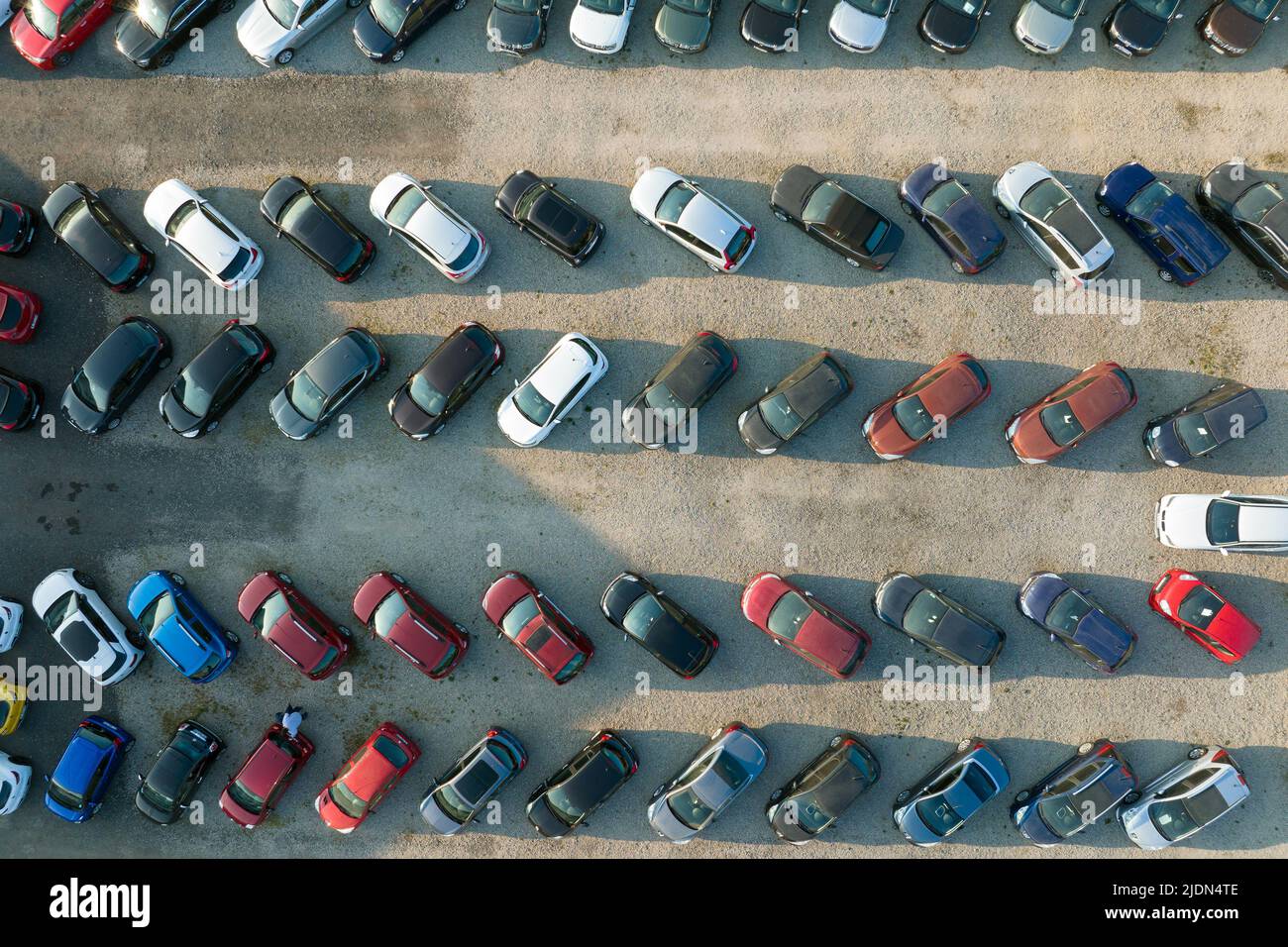 Aerial view of many colorful cars parked on dealer parking lot for sale