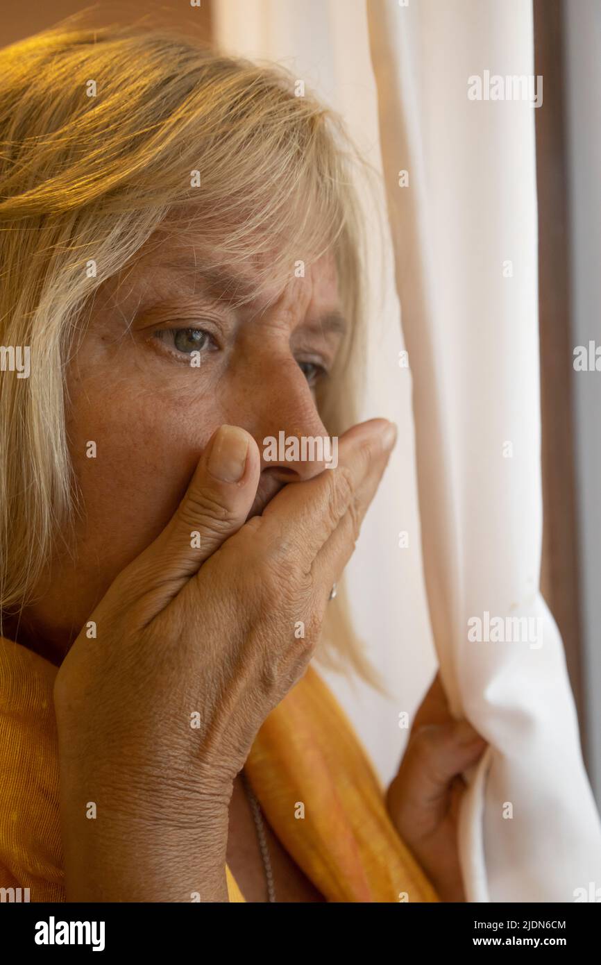 Middle-aged Caucasian woman with blond hair by a window. Authentic non-model woman. Stock Photo
