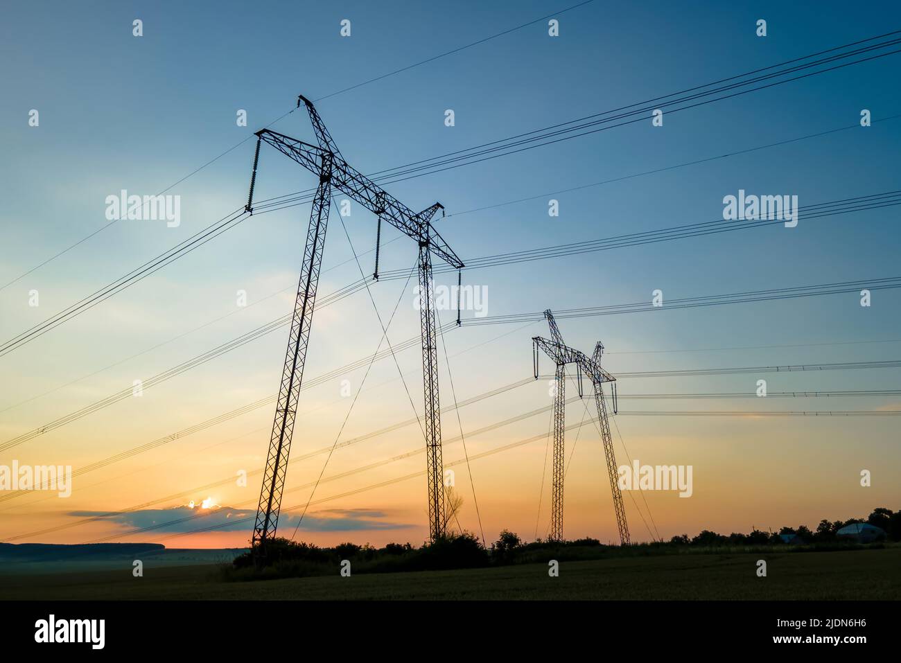 Dark silhouette of high voltage towers with electric power lines at ...