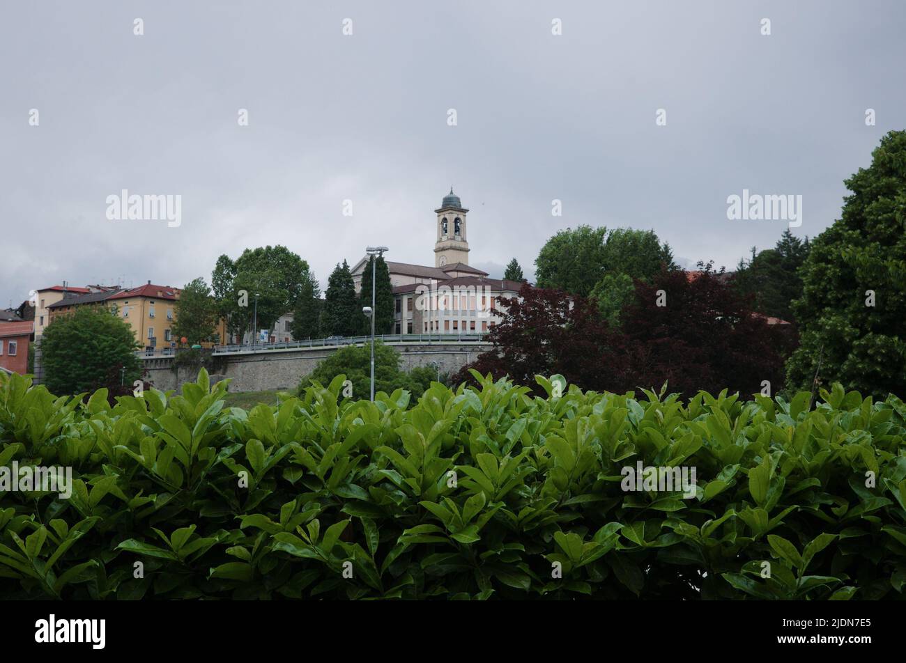 View of bell tower of Parrocchia Sant Antonino church in Borgo Val di Taro town, Parma Province, Italy. View through lush foliage to Via lungo Taro Stock Photo