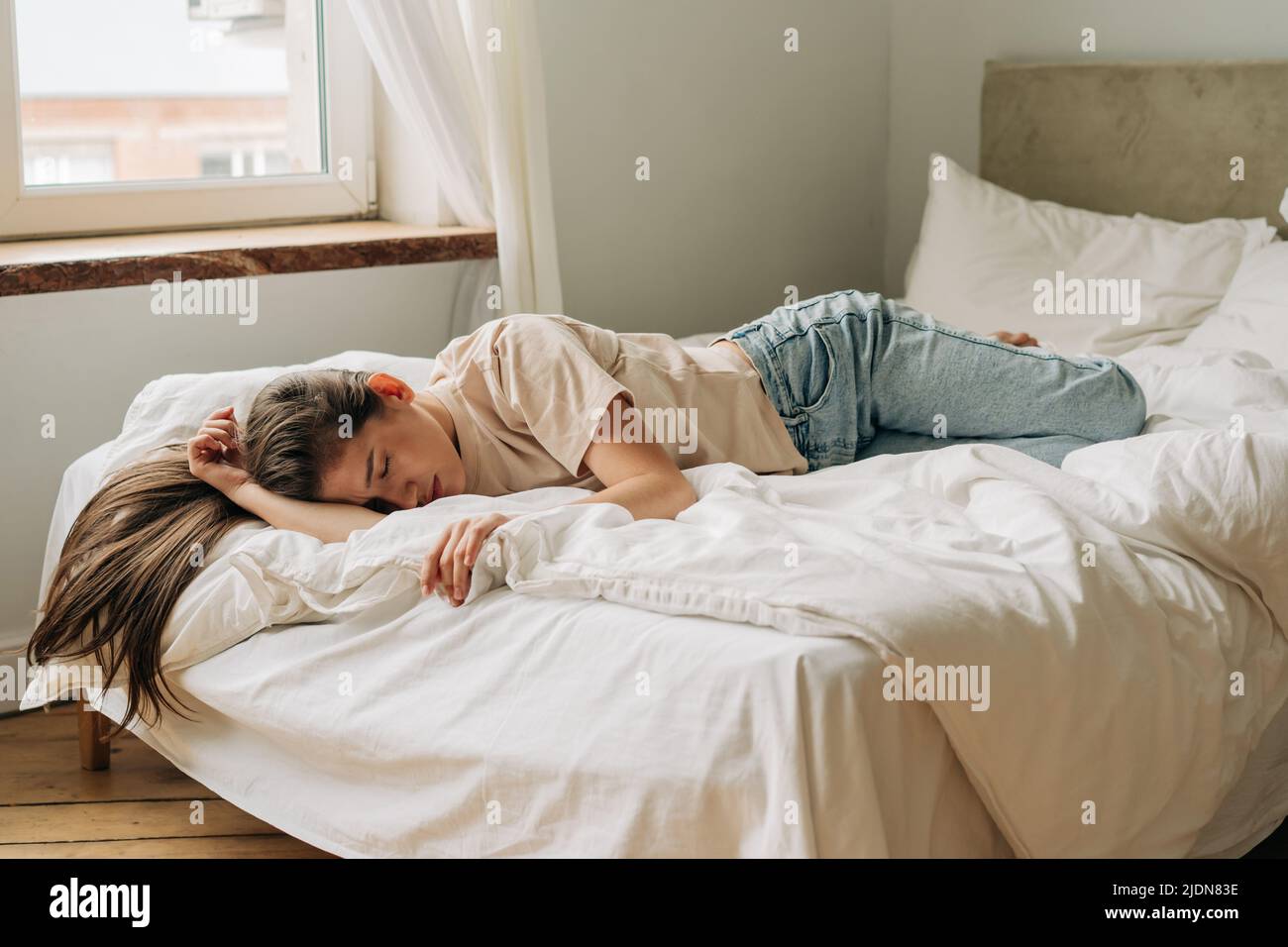 Depressed frustrated young woman is sad lying on the bed during the day. Stock Photo