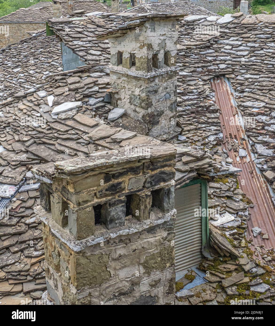 Chimneys and rough flag tiled roof of a house in the mountain village of Tsepelovo in the Zagori region of the Pindus Mountains of Greece Stock Photo