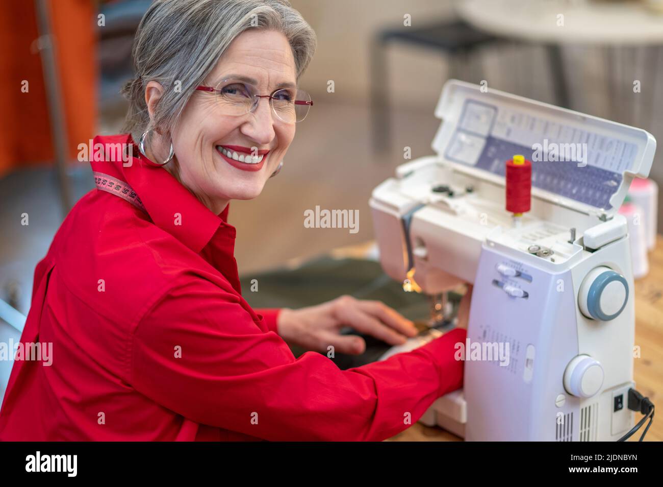 Woman sitting at sewing machine turning at camera Stock Photo Alamy
