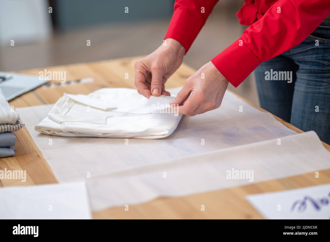 Hands touching folded clothes on surface of table Stock Photo
