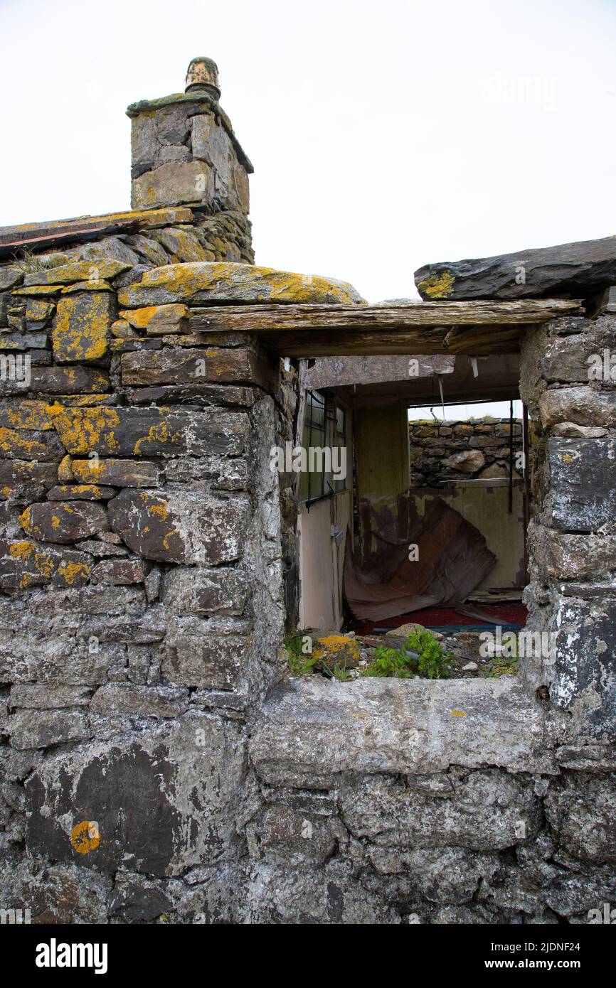 Close up of lichen covered stone derelict cottage with missing window and remaining chimney stack and rubble within on North Uist, Scotland Stock Photo