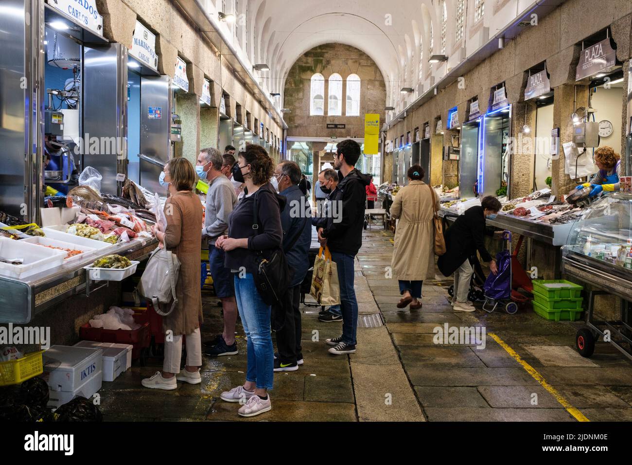 Spain, Santiago de Compostela, Galicia. Customers at a Seafood Vendor's Stand in the Market. Stock Photo
