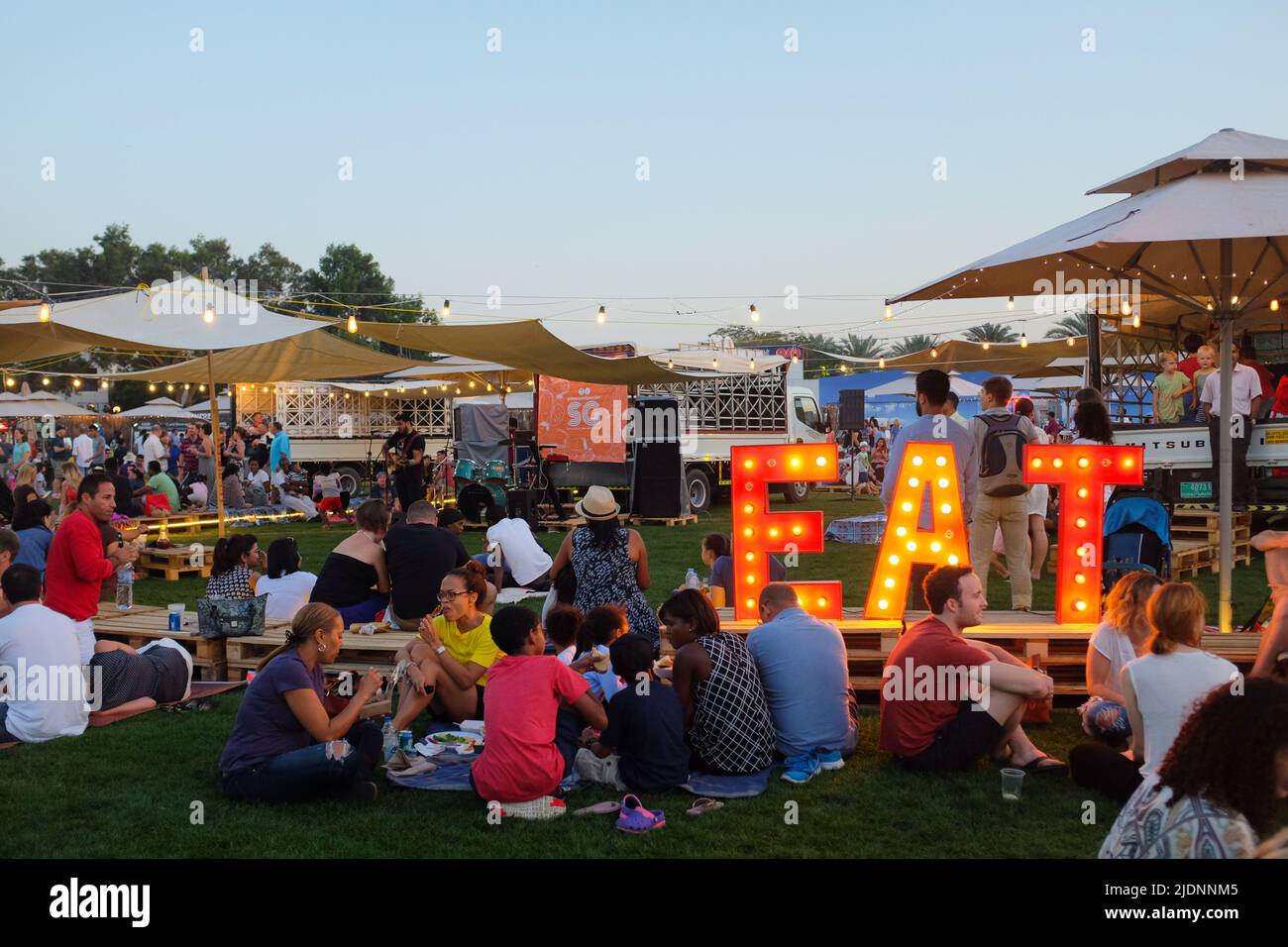 Dubai, UAE - March 26, 2016: groups of people gathered for the Food Truck Jam, an outdoor event with food trucks and live music at Emirates Golf Club. Stock Photo