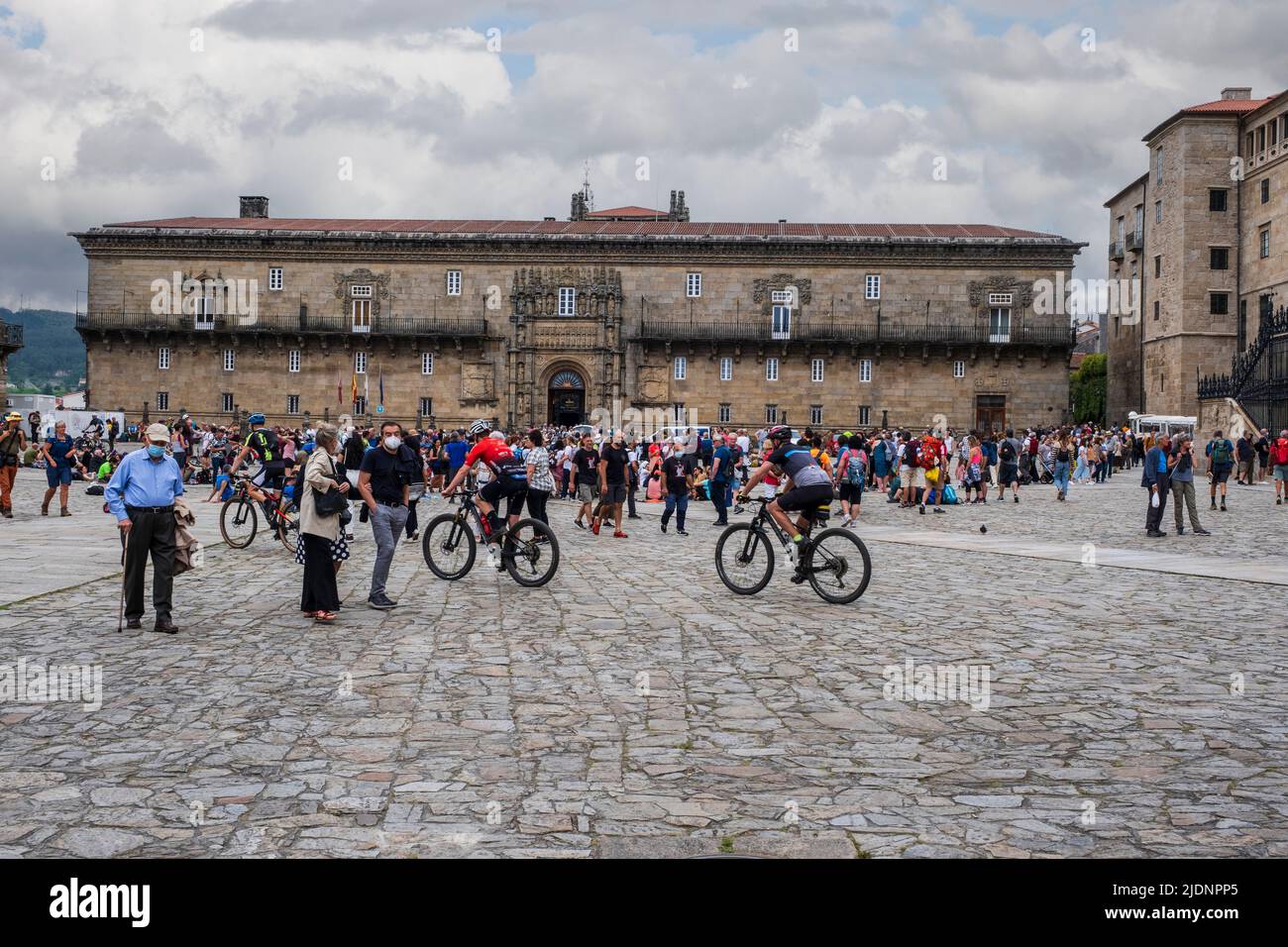Spain, Santiago de Compostela, Galicia. Pilgrims in the Praza do Obradoiro (Plaza de Obradoiro), Hostal de los Reis Catolicos, in background. Stock Photo