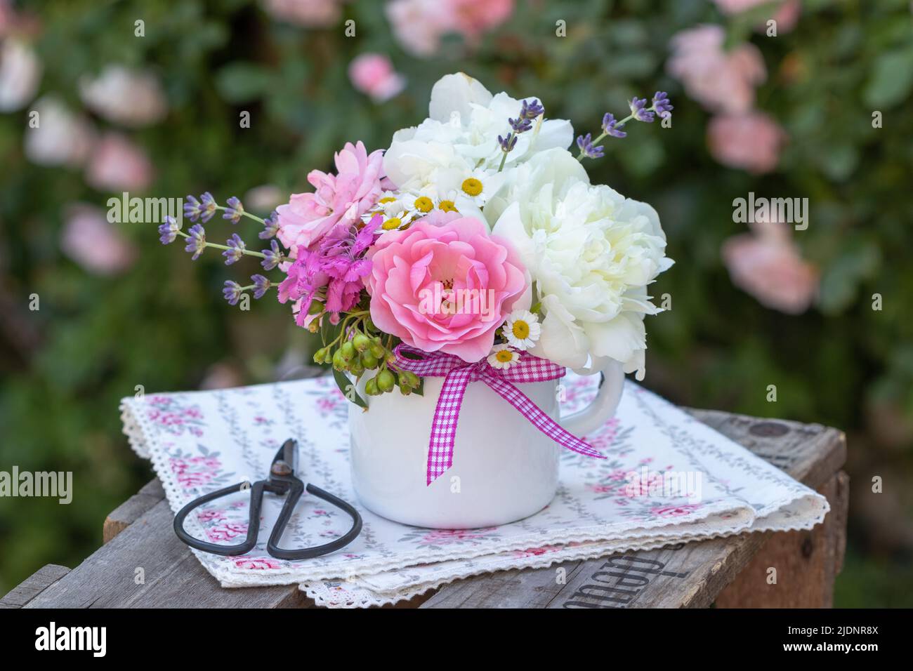 bouquet of pink roses and white peony flowers in vintage enamel cup Stock Photo