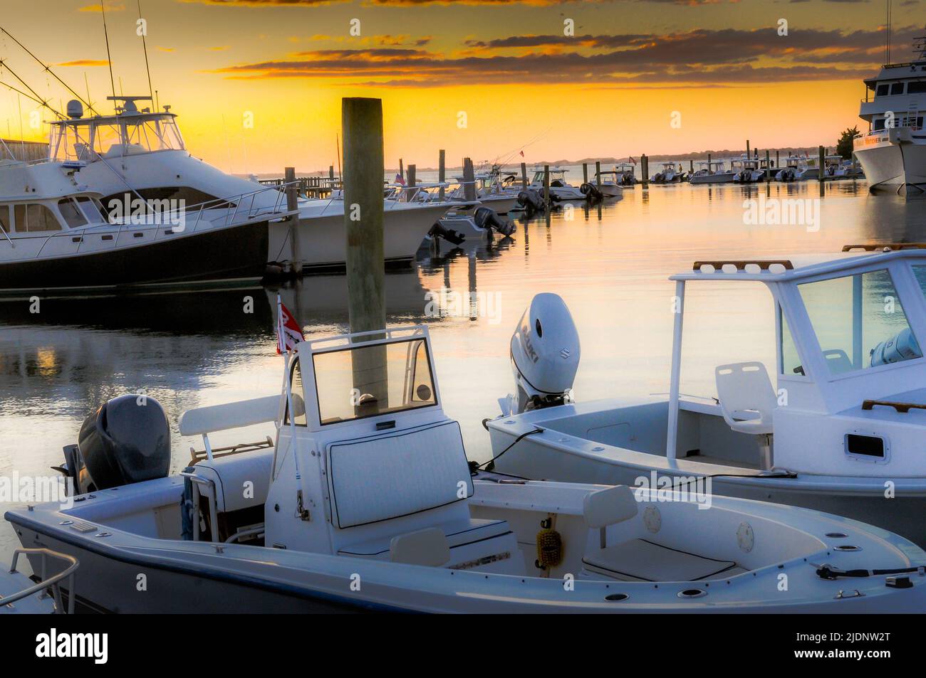 The sun sets on Barnstable Harbor full of boats of all sizes, showing the the Summer season is taking place on Cape Cod Massachusetts. Stock Photo