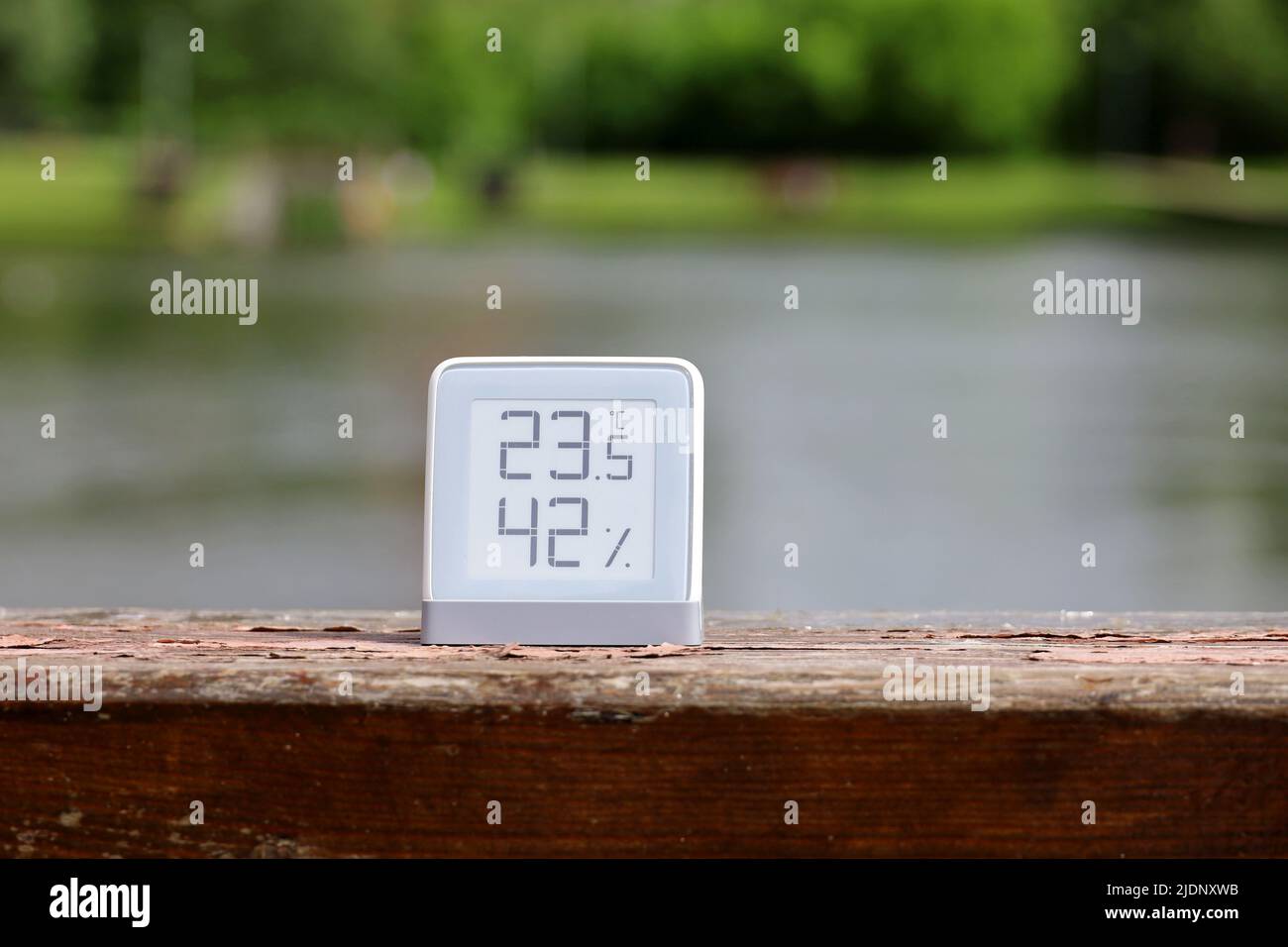 Thermometer with function of measuring humidity on the lake shore. Display with e-ink technology, hot summer weather for leisure in park Stock Photo