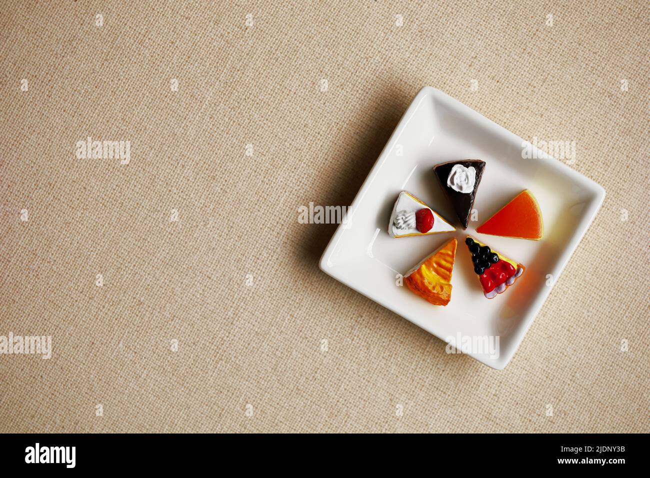 Miniature model of colorful sweets lined up on a white square plate Stock Photo