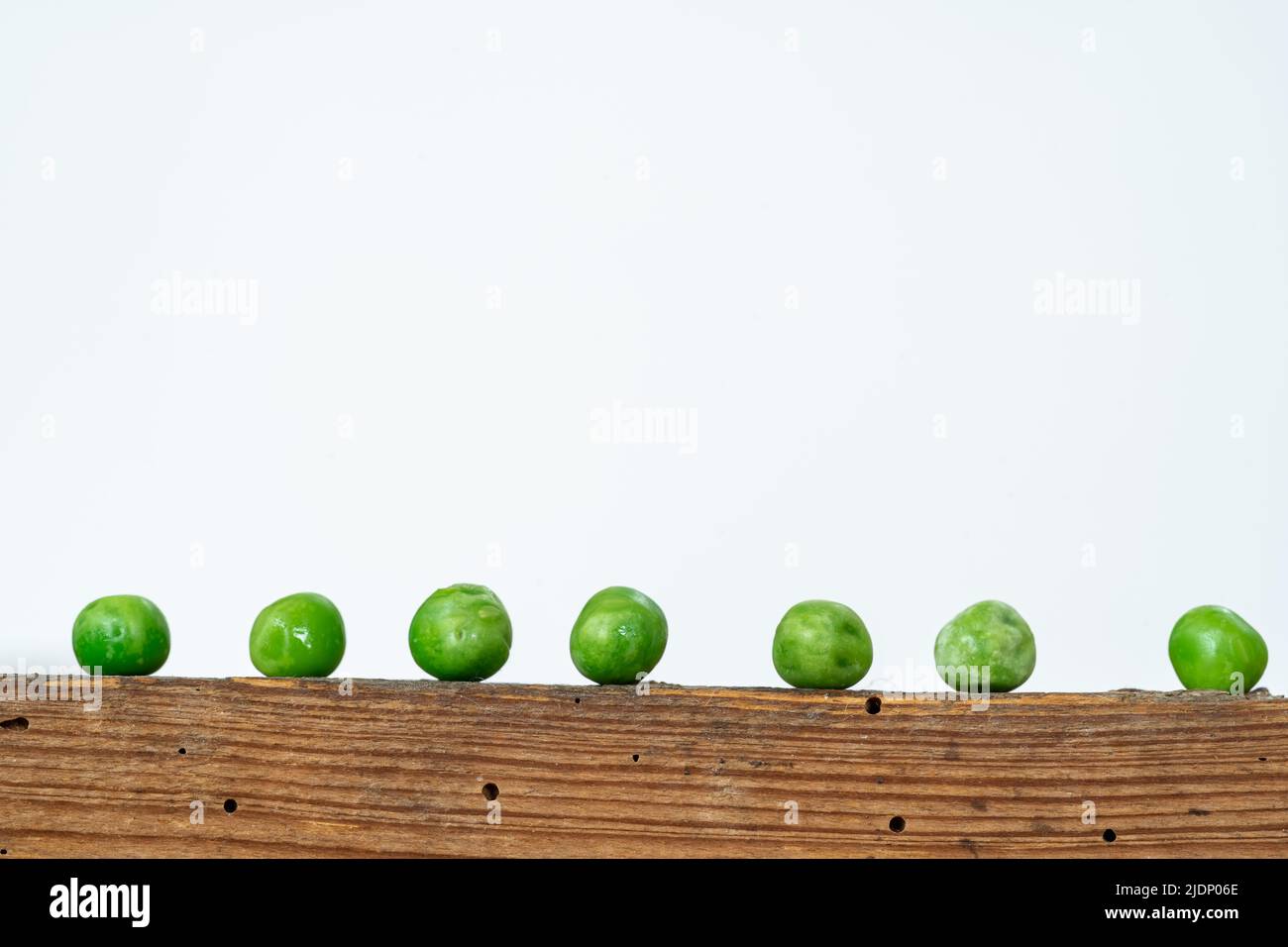 green peas lined up on top of a retro wooden box with white background. copy space for text Stock Photo