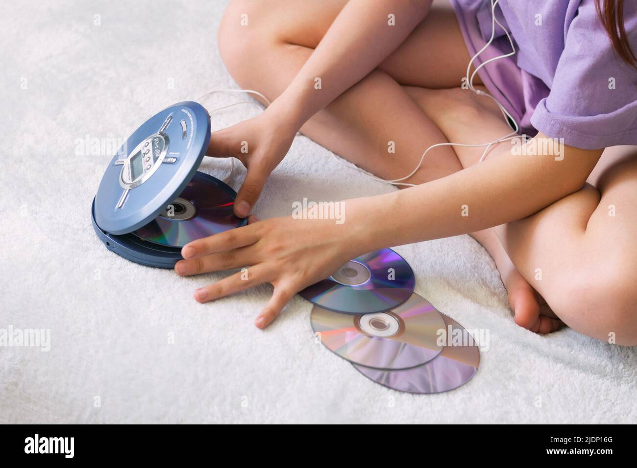 Girl connects headphones to CD player to listen to music. Recreation entertainment leisure teenager Stock Photo