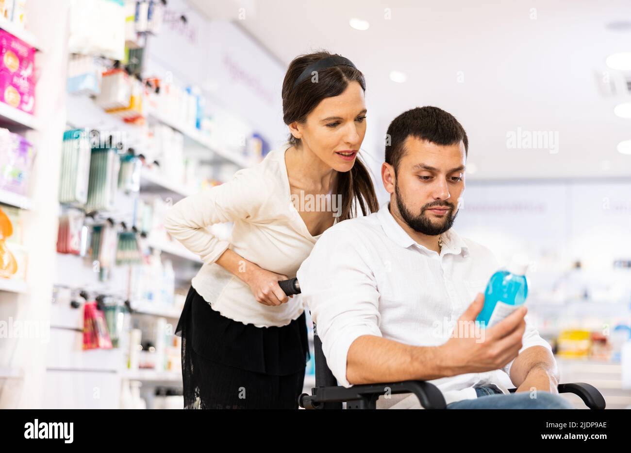 Courteous woman helping man in a wheelchair to choose the right