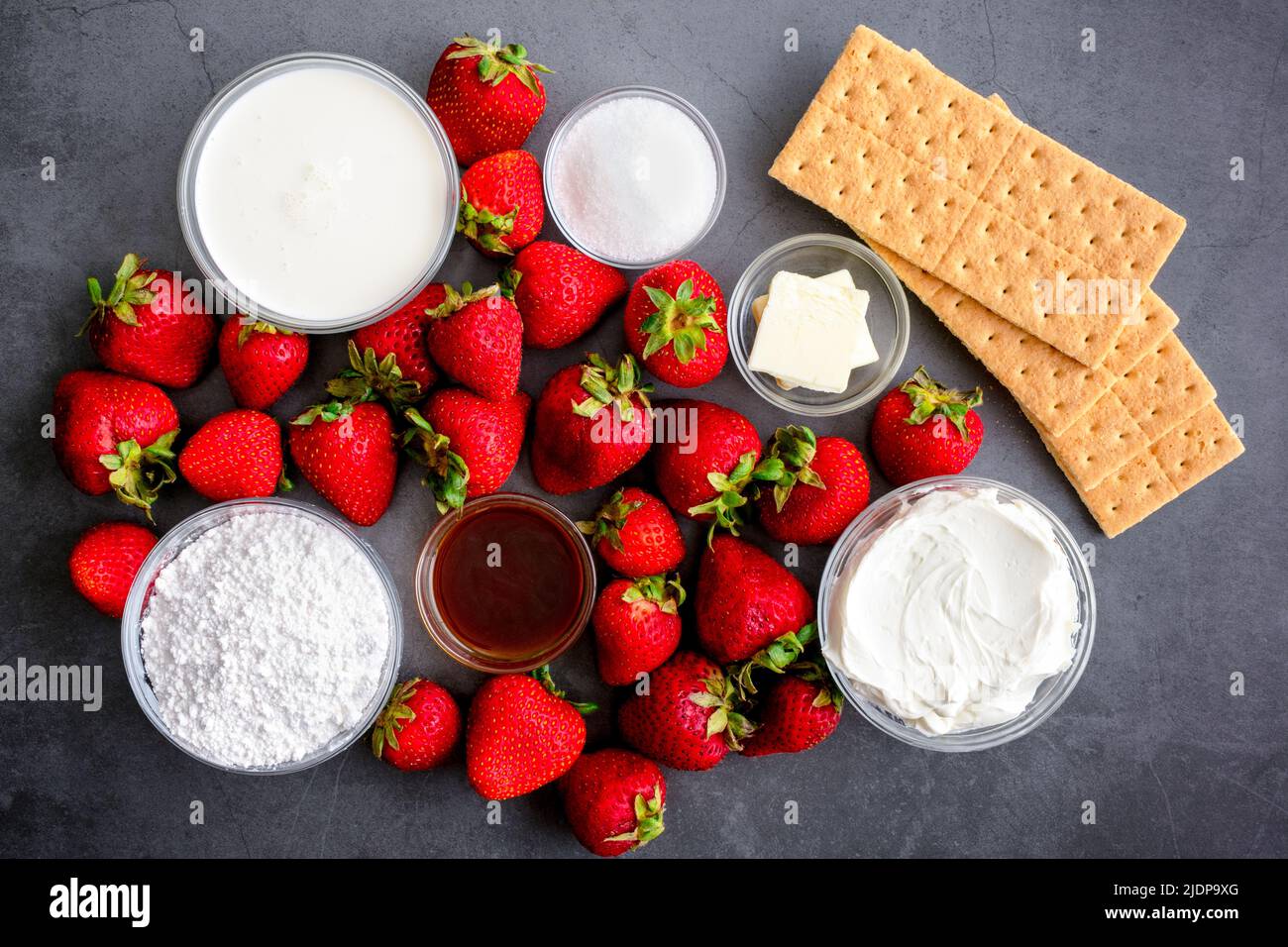 Strawberry Cheesecake Mousse Ingredients on a Dark Background: Fresh strawberries, cream cheese, graham crackers, and other dessert ingredients Stock Photo