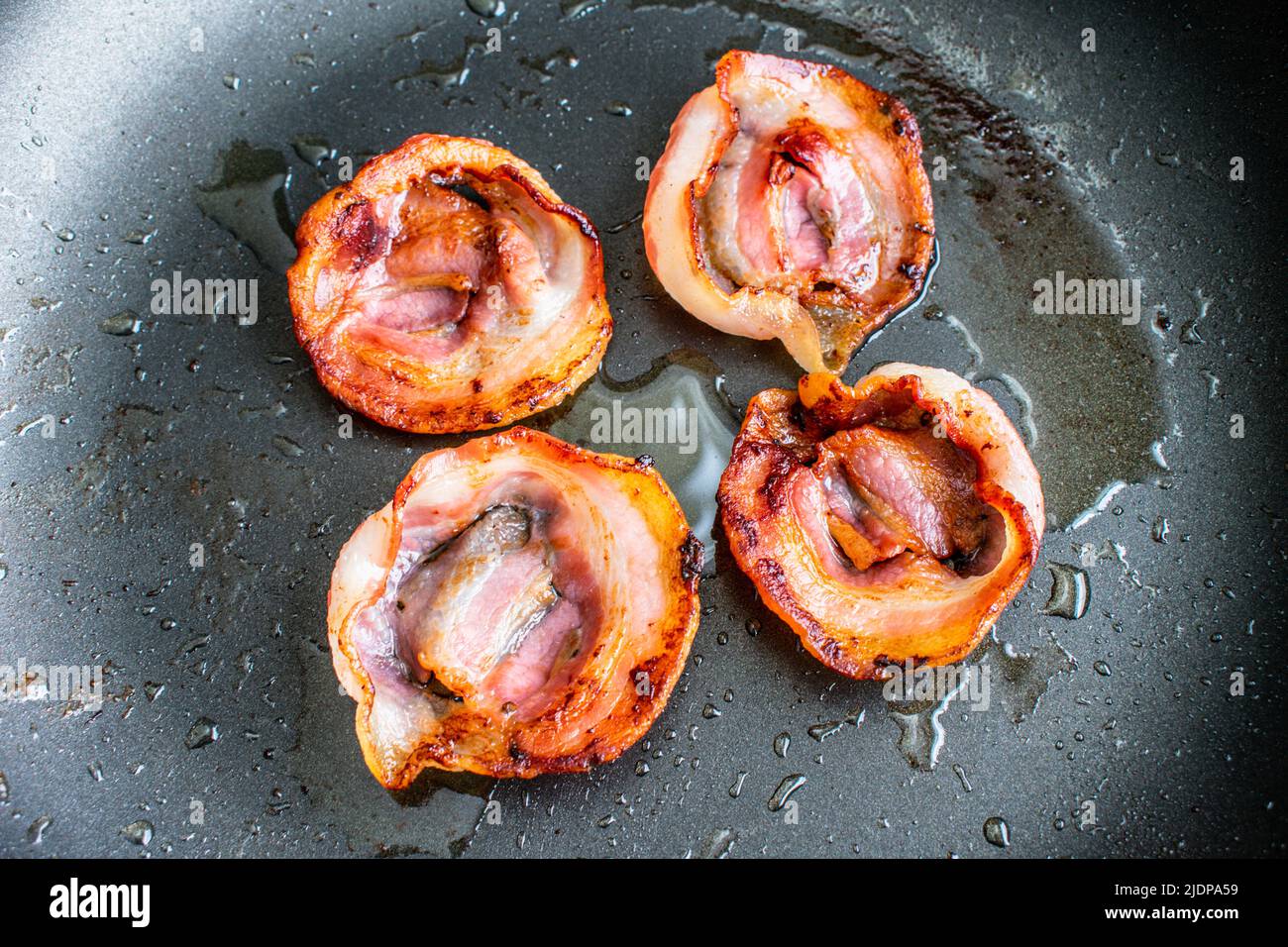 Fried Slices of Pancetta in a Nonstick Frying Pan Overhead view of