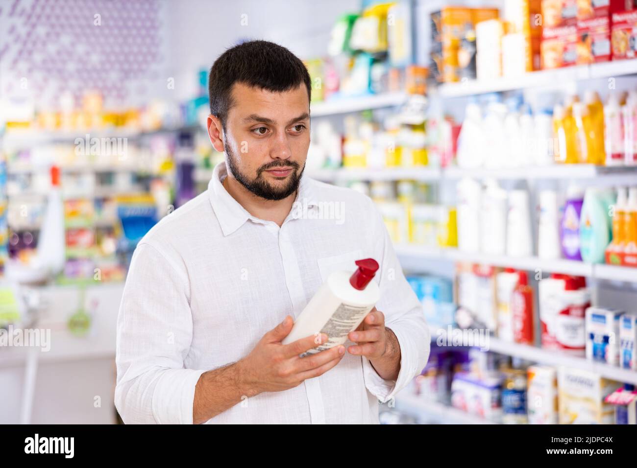 Positive man carefully studying the instructions on bottle of disinfectant Stock Photo