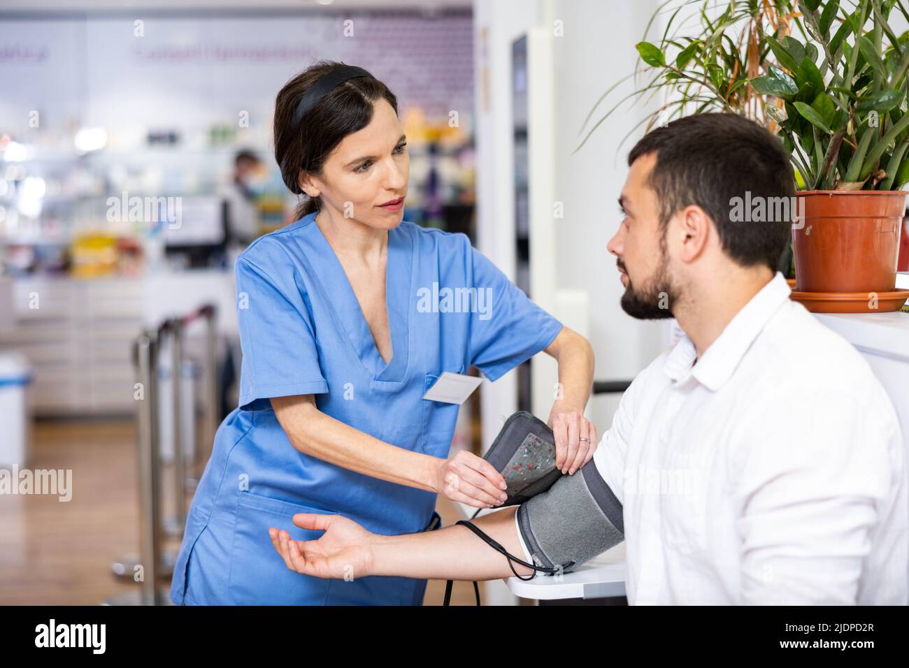 Pharmacist measures arterial blood pressure with a tonometer in man Stock Photo