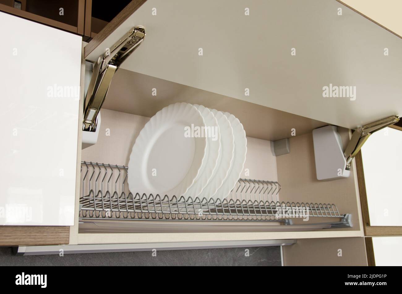 Dish dryer integrated in a wall cabinet with a door that opens upwards. Stock Photo