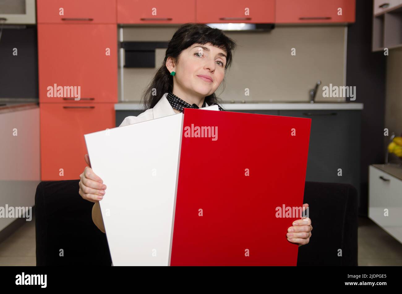 The woman shows samples of coatings for the kitchen set to choose the right combination of colors Stock Photo