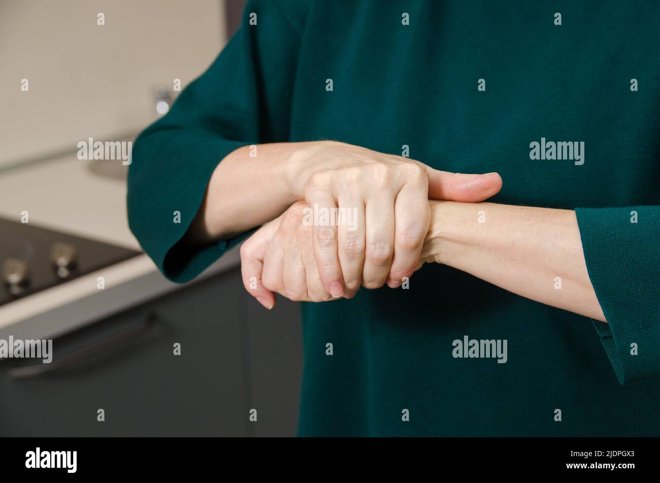 An unrecognizable woman applies cream to the hands of her hands after washing the dishes. Protecting and restoring the skin Stock Photo
