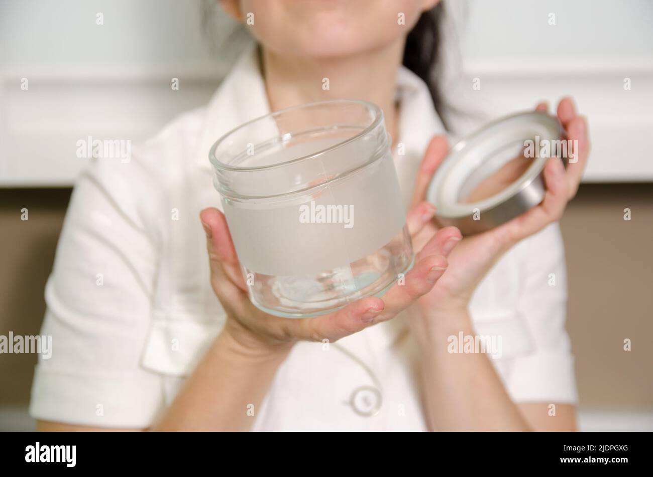 A woman is holding an open empty glass spice jar in her hands Stock Photo