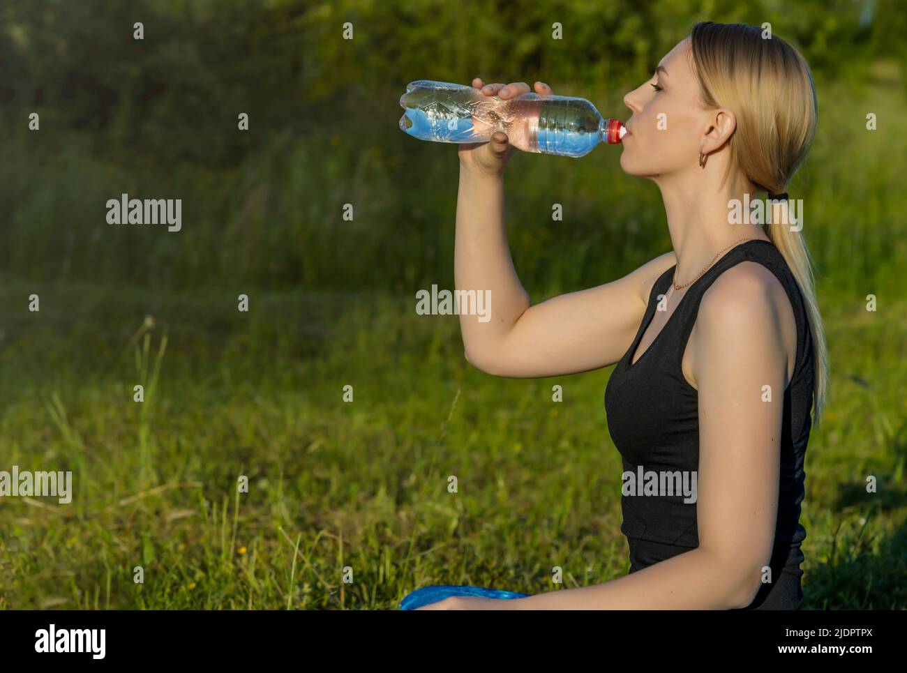 The girl drinks water after a morning workout. Stock Photo