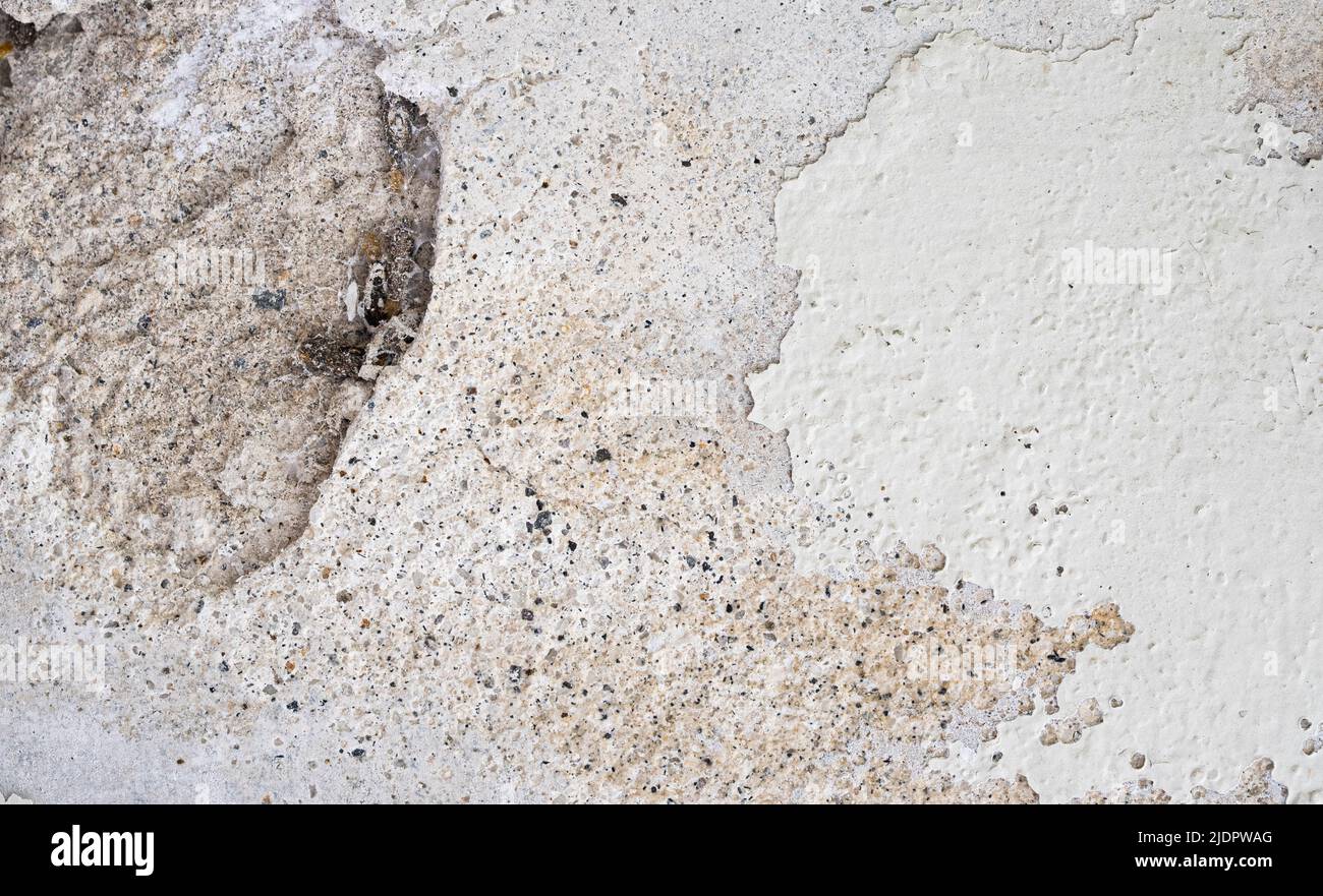 Close up of deteriorated wall with paint peeling off and holes on the concrete Stock Photo