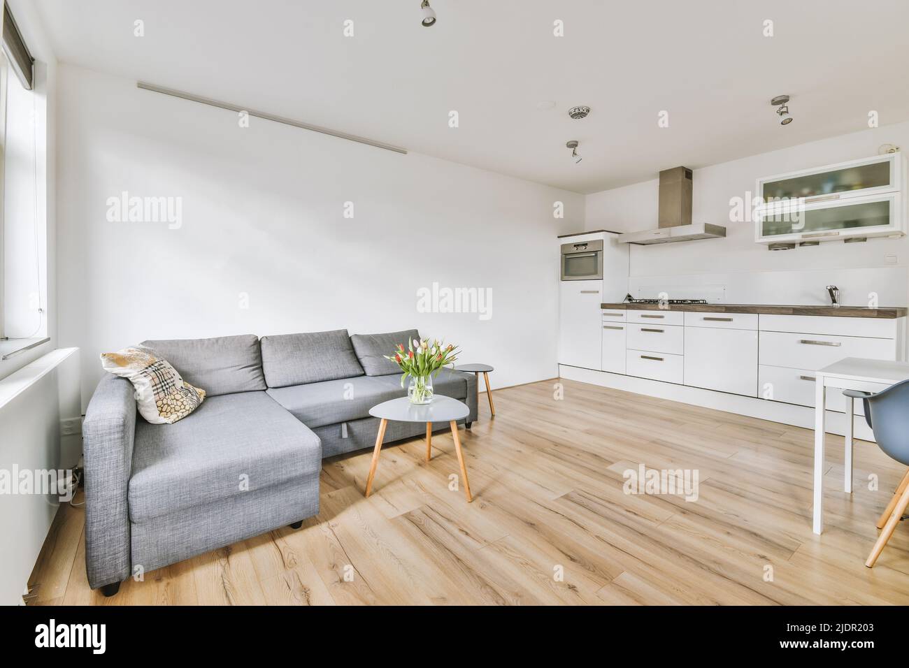 Simple open plan kitchen with white cabinets and living room with gray ...