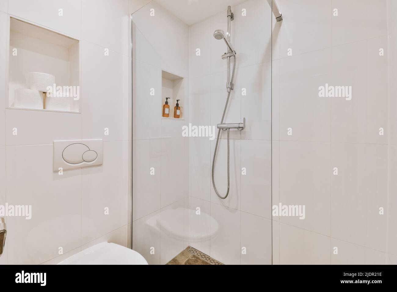 Glass partition between shower tap and wall hung toilet in modern
