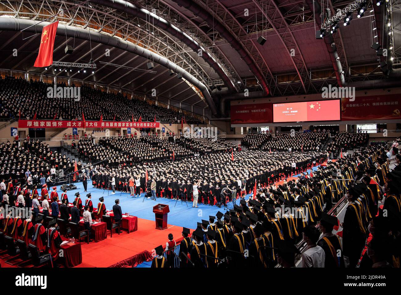 Wuhan, China. 22nd June, 2022. More than 7100 Chinese students from  Huazhong University of Science and Technology sing the national anthem  together during the graduation ceremony at the school's gym. Over the