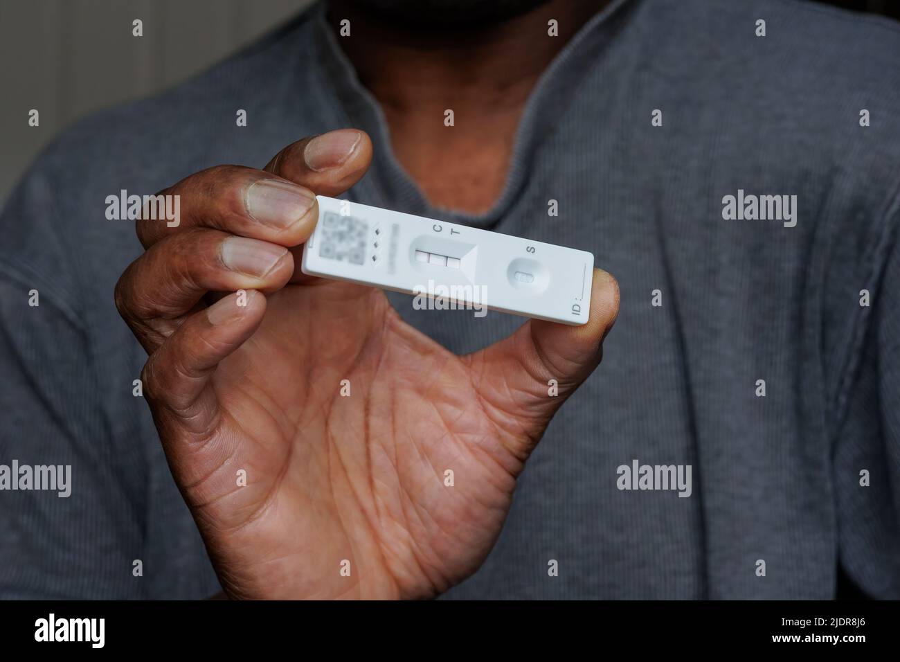 Person of African ethnicity holding a single positive Covid-19 rapid home lateral flow antigen test Stock Photo