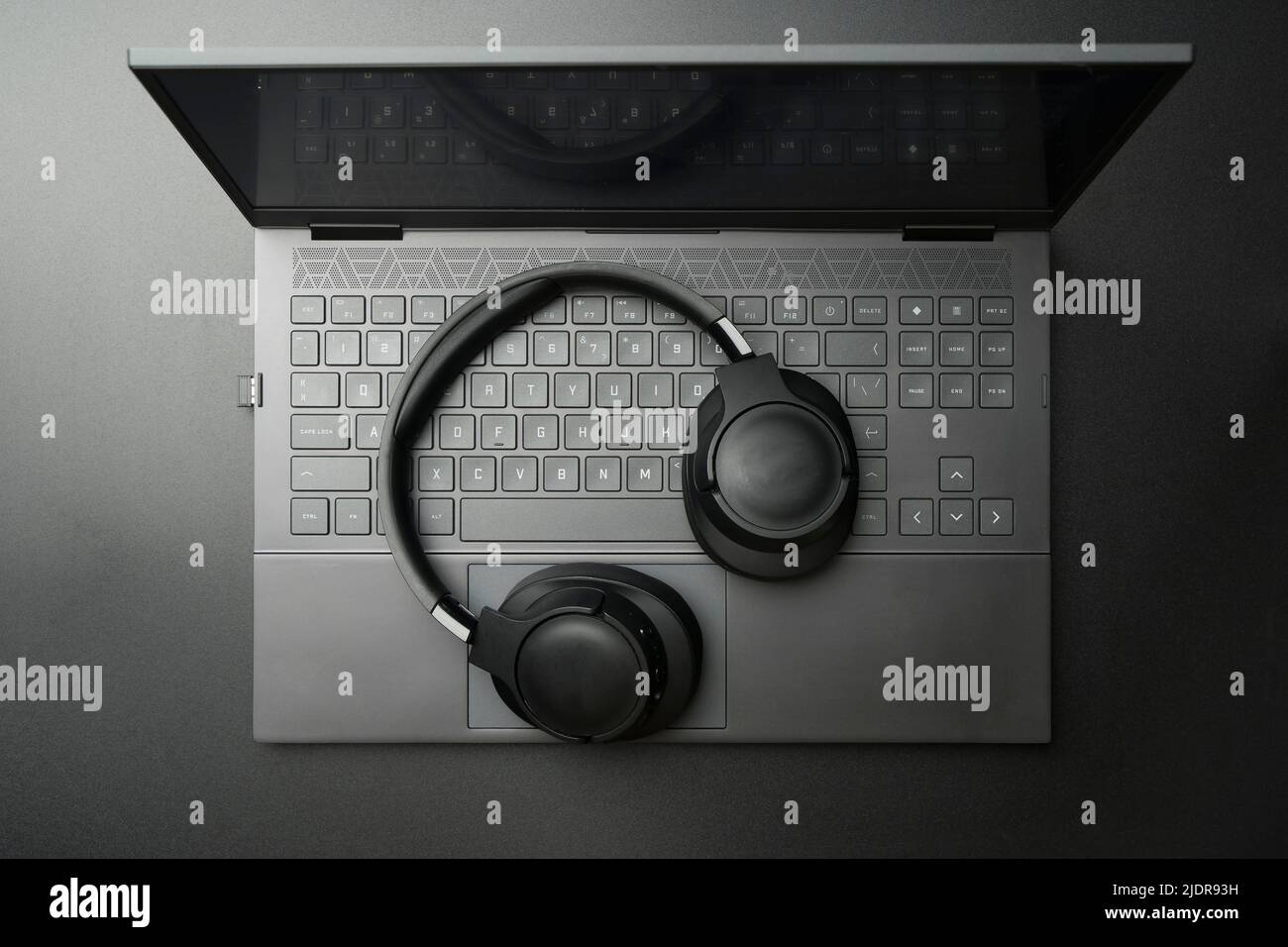 Headphones and laptop computer on black desktop. Listening to music ...