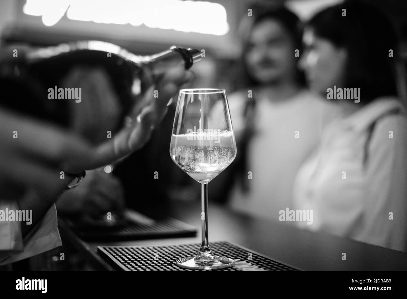 Shallow depth of field (selective focus) details with sparkling wine being poured into a glass at a bar. Stock Photo