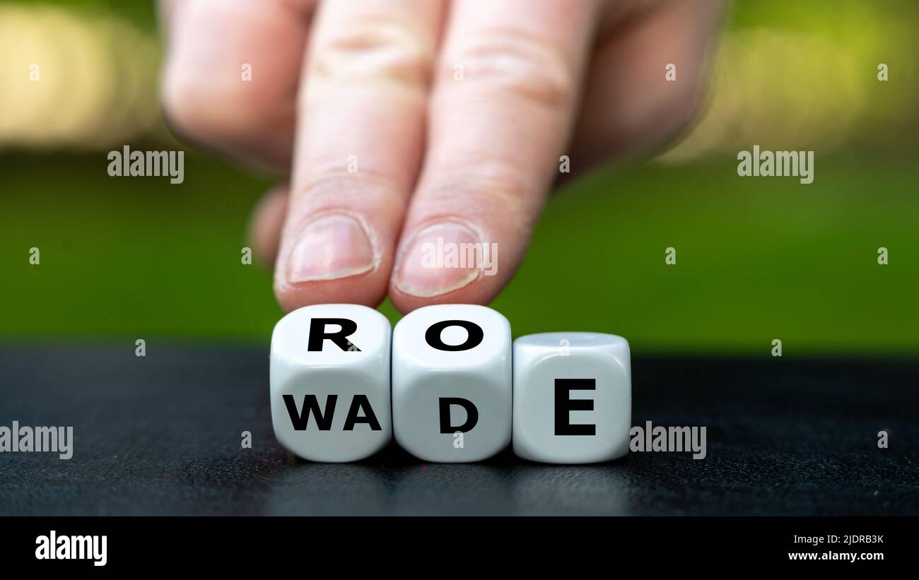 Symbol of the abortion process Roe versus Wade. Hand turns dice and changes the word Wade to Roe. Stock Photo