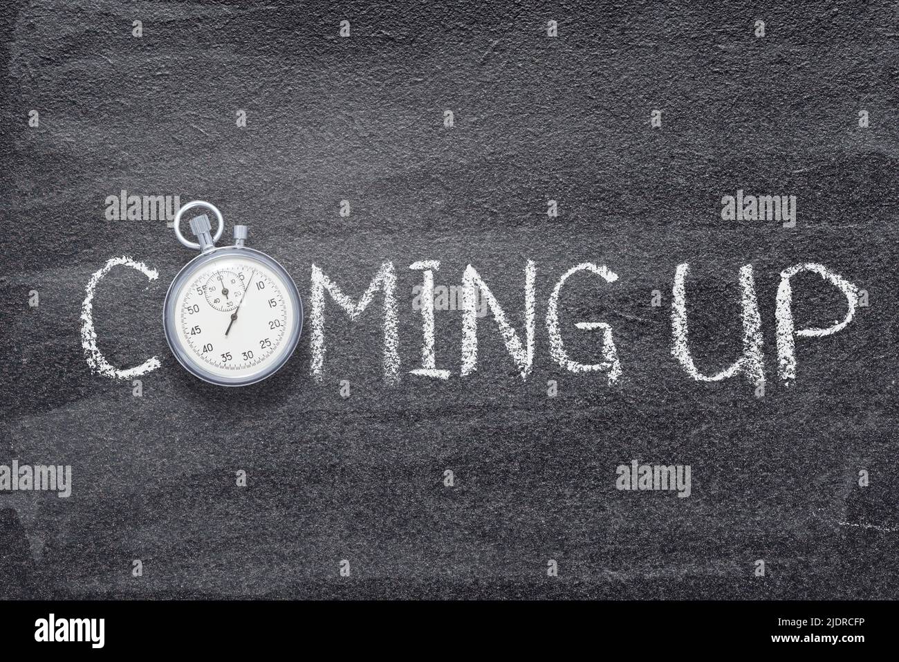coming up phrase written on chalkboard with vintage precise stopwatch Stock Photo