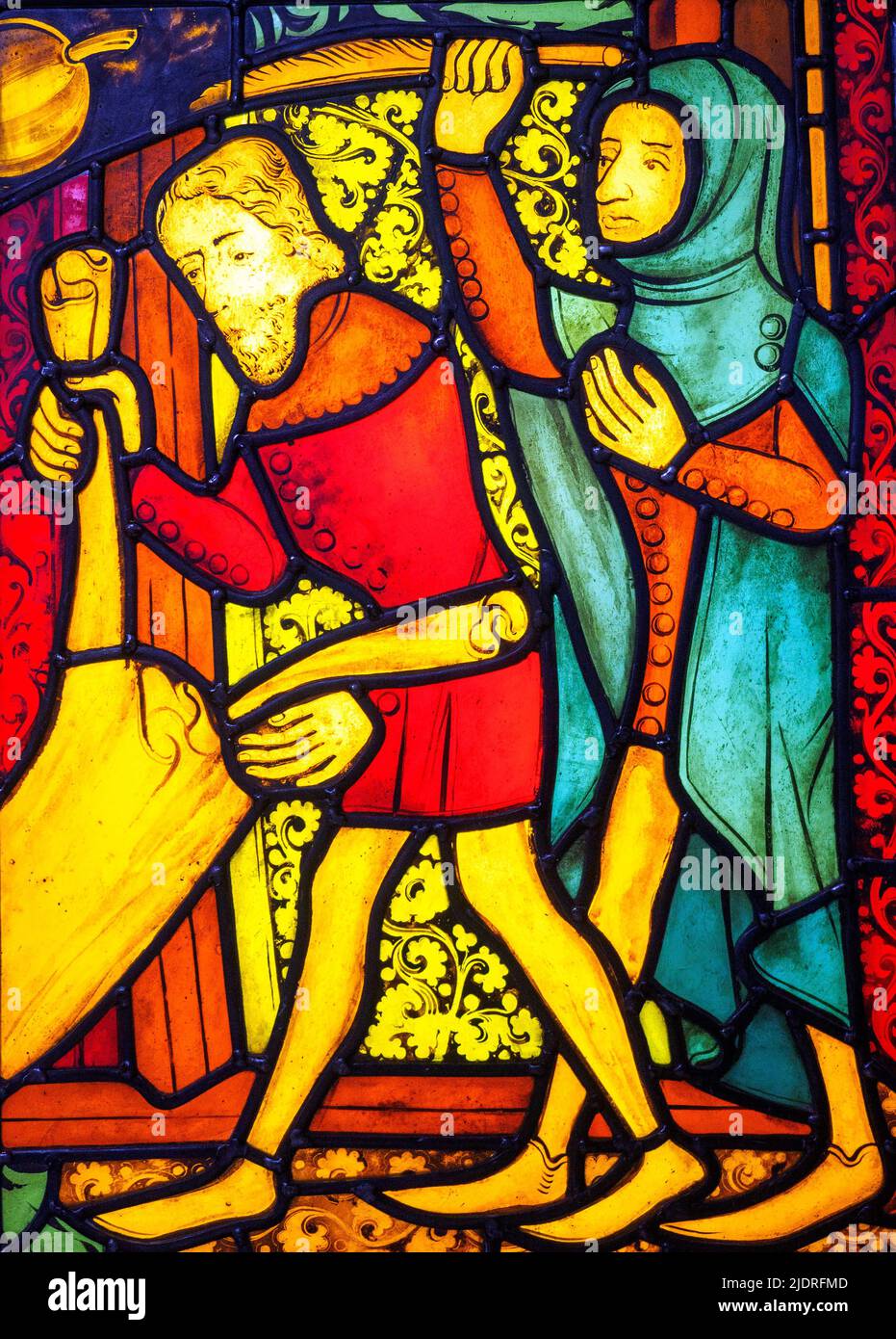 Replica of a piece of stained glass from about 1375. The otiginal was part of a larger window showing christ's entry into Jerusalem. The man on the left holds a garment that was laid out on the ground to welcome Christ. The man  on the left right holds a palm branch.  Lead strips hold the separate pieces of glass together and are part of the design. The strips are smooth with raised, soldered joins. The smooth glass is a block of solid colour. The textured glass has been decorated with enamel paints and then fired. Stock Photo