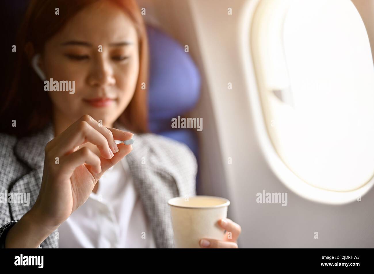Young Asian female passenger feeling dizzy, taking an airsick motion