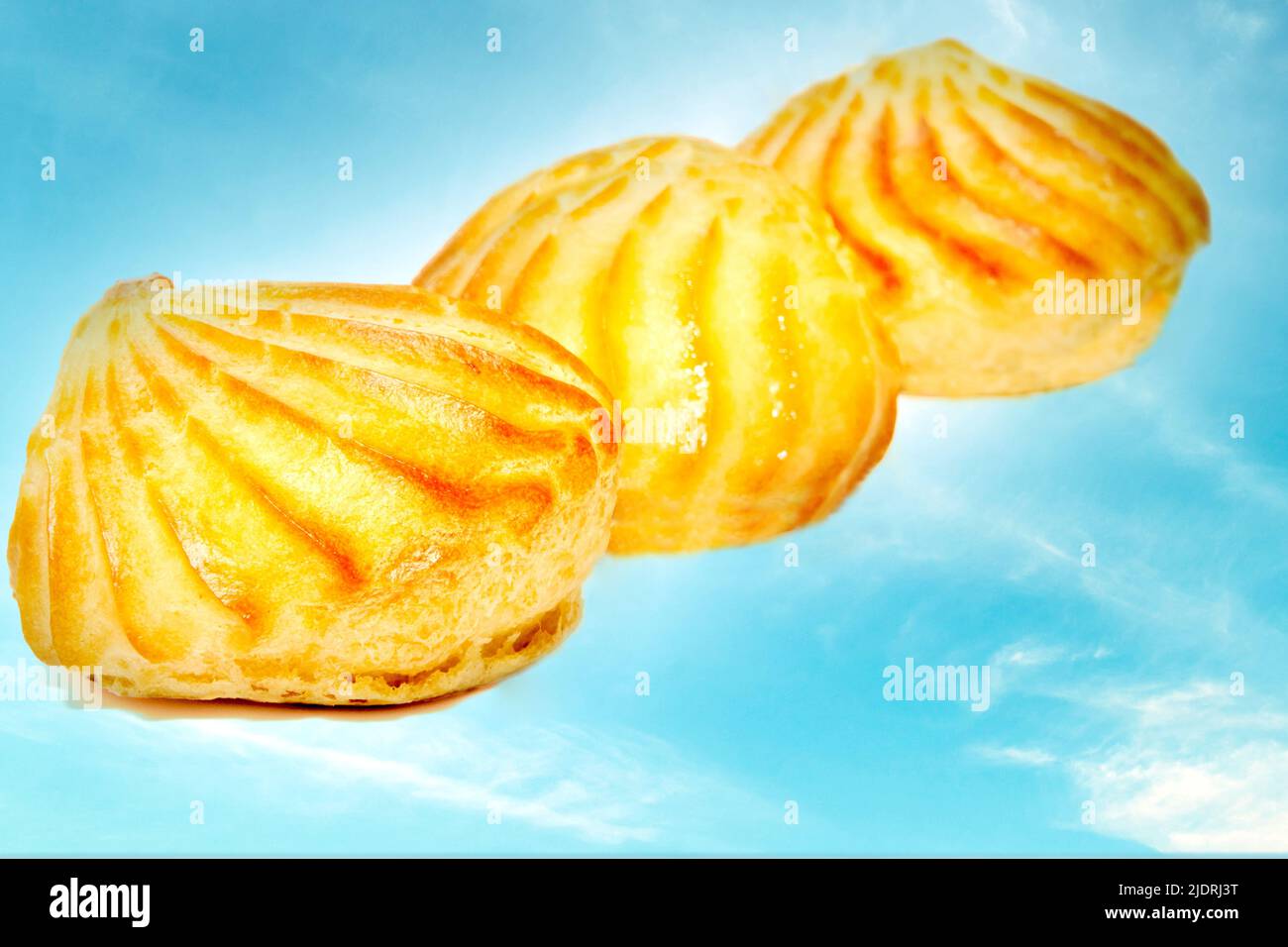 Three pink delicious appetizing profiterole eclair cakes on a sky background Stock Photo