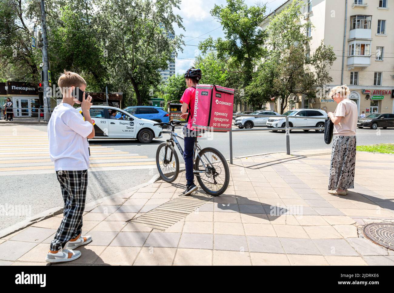 Samara, Russia - June 18, 2022: Courier of Samokat food delivery service on bicycle at the city street Stock Photo
