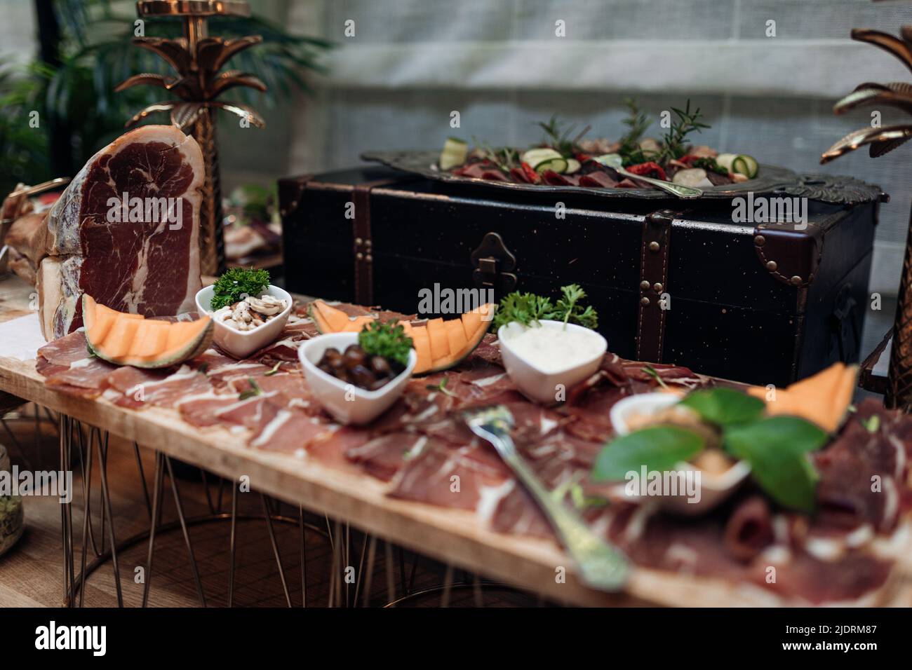 Serving and food exhibition of types of smoked meat and jerky with beautiful decor on stand closeup. Portion of meaty appetizer, nutritious dish. Food Stock Photo