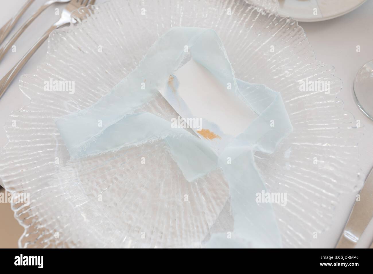 Festive table setting with card for name on white tablecloth closeup. Place identity, decorated hall, event celebration. Holiday, elegant and luxury Stock Photo