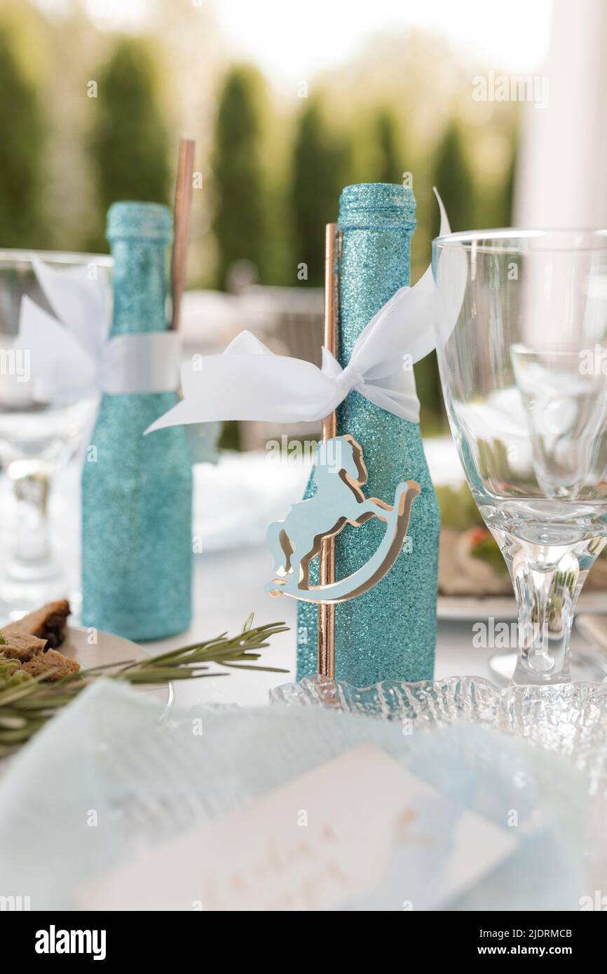 Festive table setting with decorated brilliant blue bottle of drink on white tablecloth closeup. Decorations, event celebration. Holiday, elegant and Stock Photo
